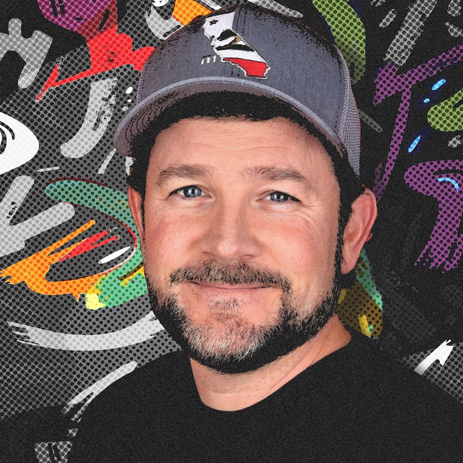 Eric, wearing a California trucker cap, in front of a colorful graffiti wall.